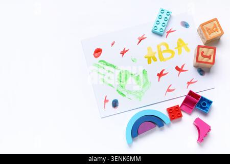 Kinder farbenfrohe Handabdrücke mit Alphabetblöcken und Bauziegeln auf weißem Hintergrund, frühkindliche Erziehung und kreatives Spiel Stockfoto