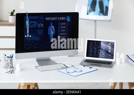 Digitale Patientenkarte-Schnittstelle auf dem Computerbildschirm mit medizinischen Daten und Stethoskop in der Arztpraxis hängt ein Stethoskop am Monitor und ein Lapto Stockfoto