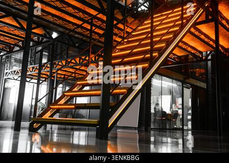 Moderne industrielle Innenarchitektur mit beleuchteter Treppe und freiliegendem Metallgestell in einem modernen Bürogebäude Stockfoto