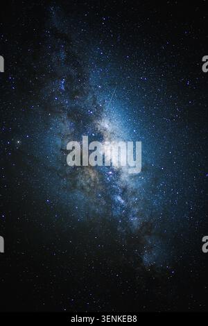 Eine atemberaubende vertikale Aufnahme der Milchstraße-Galaxie, beleuchtet von unzähligen Sternen und mit Meteoren übersät, vor einem tiefblauen Nachthimmel. Stockfoto