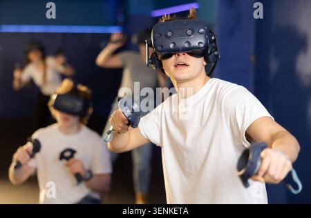 Freunde, die ein Virtual-Reality-Headset verwenden und Joysticks steuern Stockfoto
