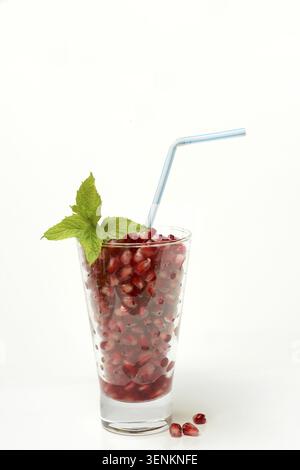 Granatapfelsamen in Glas und Stroh, halbierter Granatapfel Stockfoto