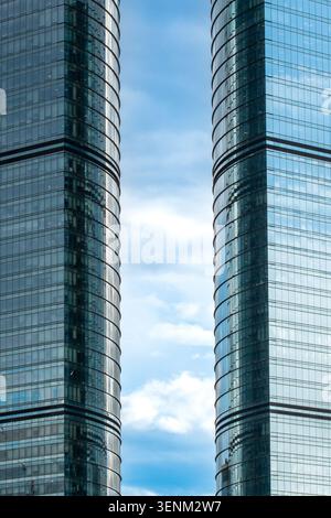 Flacher Blick auf zwei Geschäftsgebäude mit reflektierenden Glasfenstern unter hohem Himmel Stockfoto
