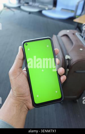 Hand hält ein leeres Smartphone in einem Flughafen Stockfoto