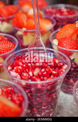 Farbenfrohe Früchte werden in klaren Bechern an einem Stand ausgestellt Stockfoto