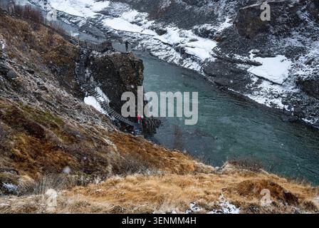Touristen erkunden den verschneiten Studlagil River Canyon und die Wasserfälle, ein beliebtes Reiseziel in Island Stockfoto