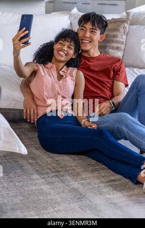 Paare posieren für Werbeaktion, Frau hebt das Telefon und macht Selfie, animierte Herzen schwebend um Paare Stockfoto