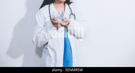 Porträt einer asiatischen Ärztin, die eine Kaffeetasse auf weißem Atelierhintergrund hält Stockfoto