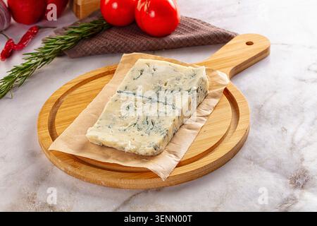 Italienischer Gorgonzola-Käse auf Holzbrett mit frischem Rosmarin und Tomaten auf Marmoroberfläche Stockfoto