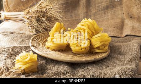 Rohe Tagliatelle-Pasta Nistet Auf Weidenschale Mit Weizenohren Stockfoto