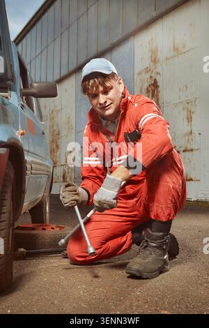 Niedlicher Mann in Rot, der sein schönes Retro-Auto tanzt Stockfoto