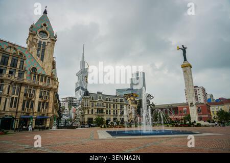 Ein Weitwinkelblick auf den Europaplatz in Batumi, Georgia, mit dem prominenten Medea Monument und einem lebhaften Brunnen. Der kunstvolle Chacha Tower und der Stockfoto