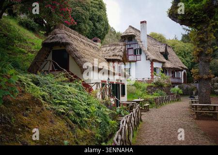 Queimadas Forest Park in Santana, Madeira Island, Portugal, Europa. Blick auf die rot-weißen Häuser mit Satteldach und Holzzaun im Vordergrund Stockfoto