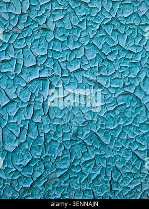 Die detaillierte Textur alter türkisblauer Farbe. Der Lack hat Risse und löst sich von einer flachen Oberfläche ab, wodurch Zeit- und Wettereinflüsse erfasst werden. Stockfoto