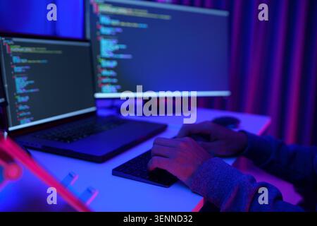Programmierer arbeitet an zwei Monitoren in Neon lit Office Stockfoto