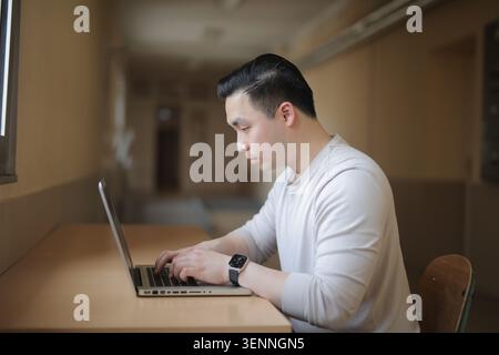 Ein junger asiatischer Mann konzentrierte sich auf seinen Laptop Stockfoto