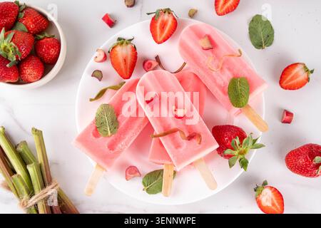 Erdbeer-Rhabarber-Eis-Eis-Eis-Eis. Gefrorenes Fruchtsorbet, Joghurt-Eis auf Sticks, mit pürierten Erdbeeren und Rhabarber und Saft, mit Zutaten o Stockfoto