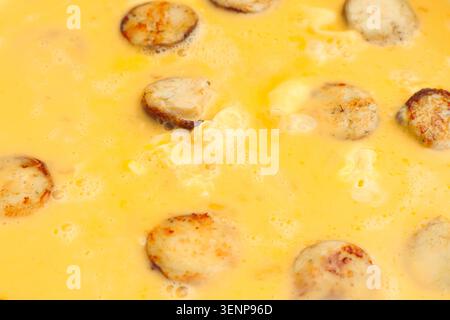 Omelette mit Wurst kochen. Flüssiges Ei für Rührei mit wird in die Pfanne gegossen. Stockfoto