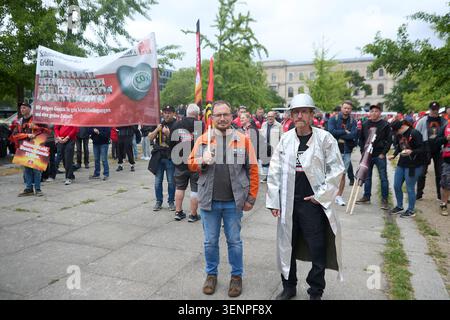 Berlin, Deutschland, 12. Juni 2026. Zwei Stahlarbeiter stehen im Vordergrund eines Protestes der gewerkschaften im Freien. Ein Arbeiter trägt eine graue Arbeitsjacke mit hellorangefarbenen Schultern, während sein Kollege einen weißen Schutzmantel und einen silbernen Hardhat trägt. Im Hintergrund versammelt sich eine große Menge von Aktivisten auf einem gepflasterten öffentlichen Platz. Ein markantes rot-weißes IG Metall-Banner wird hoch gehalten, auf dem Text über den industriellen Wandel und grüne zukünftige Initiativen angezeigt wird. Die Szene zeigt Solidarität, Arbeitnehmervertretung und aktive Arbeitsstreitigkeiten. Quelle: Felix Wolf/Alamy Live Stockfoto
