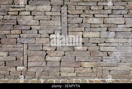 Trockenwand aus unregelmäßigen Flachsteinen aus Porphyr. Farben sind Violett-, Rot- und Brauntöne. Hintergrund und Textur. Stockfoto