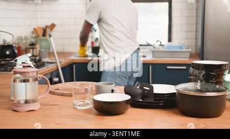 Mann, Der Geschirr In Der Hausküche Mit Schmutzigem Geschirr Und Töpfen Auf Hölzerner Arbeitsplatte Wäscht Stockfoto