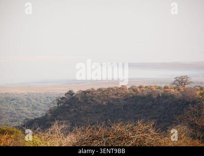 Wenn Sie von den hohen Klippen des Rift Valley hinunterblicken, setzt sich ein leichter Nebel über dem alkalischen Wasser des Lake Manyara ab. Stockfoto