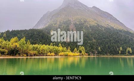 Sharp Mountain Peak mit gelben Herbstbäumen, die sich im Green Lake spiegeln Stockfoto