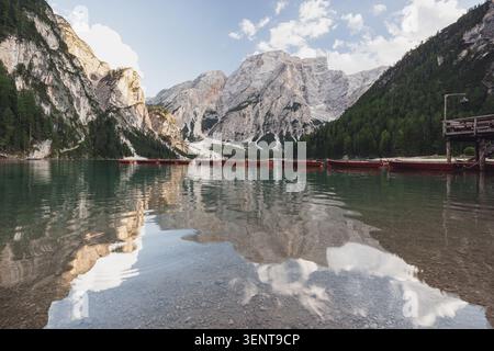 Ein Weitwinkelblick auf den Pragser Wildsee in der Abenddämmerung. Das ruhige, durchsichtige Wasser offenbart das felsige Seebad im Vordergrund Stockfoto