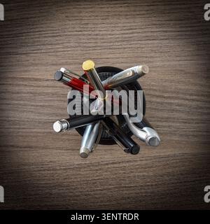 Ansicht von oben auf verschiedene Stifte und Schreibgeräte, die in einem Halter auf einer hölzernen Schreibtischoberfläche angeordnet sind. Stockfoto
