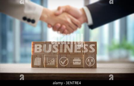 Nahaufnahme des Handschlags über Geschäftsblöcken, die Partnerschaft, Vertrauen, Zusammenarbeit, Vereinbarung und Unternehmenserfolg in einem professionellen Umfeld darstellen. Stockfoto