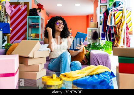 Schöne junge hispanische Frau, die ihr Heimbekleidung E-Commerce-Geschäft von zu Hause aus verwaltet - weibliche Unternehmerin besitzt Online-Shopping-Shop, Konzepte Stockfoto