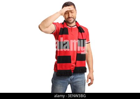 Enttäuschter Sportfan mit einem rot-schwarzen Schal, der seine Hand an der Stirn hält Stockfoto