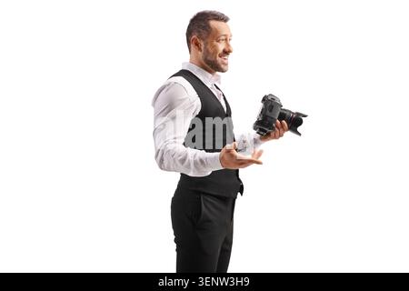 Lächelnder männlicher Fotograf, der im Profil steht und eine Kamera isoliert auf weißem Hintergrund hält Stockfoto
