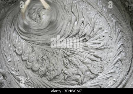 Mischung von Trockenbaumischungen mit Mischern. Nassmörtelmischung für die Endbearbeitung im Bauwesen. Spuren der Drehung des Werkzeugs, Abdrücke auf Zement. Stockfoto