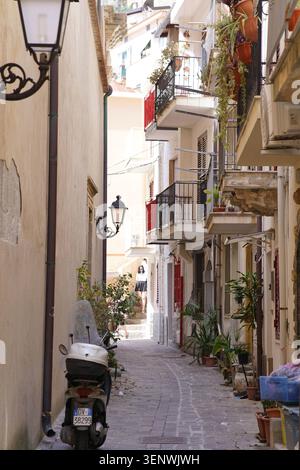 Enge Gasse mit Roller, Balkonen und Blumen in Scilla, Kalabrien, Italien an sonnigen Tagen. Stockfoto