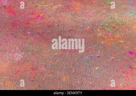Abstrakter Hintergrund mit bunten Farbspritzern, die über eine raue Betonoberfläche verteilt sind. Lebendige Textur mit leuchtenden Farben Stockfoto