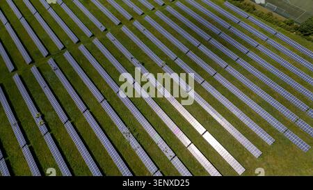 Reihen von Solarpaneelen auf einem grünen Feld, die die Infrastruktur für erneuerbare Energien in Knottingley, Großbritannien, zeigen. Stockfoto
