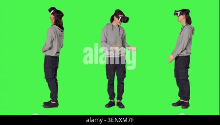Junger Mann verwendet Virtual-Reality-Technologie auf der Kamera mit Ganzkörper-Green-Screen-Vorlage, interaktive 3D-Sicht auf vr-Brillen, während moderne Menschen Spaß mit künstlicher Intelligenz-Headset haben. Stockfoto