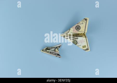 Gefalteter Dollarschein erzeugt eine zarte Schmetterlingsform. Seine Flügel ahmen den Flug nach, als ob sie bereit wären, in die Höhe zu fliegen. Der sanfte blaue Hintergrund verstärkt seine künstlerische Einfachheit Stockfoto