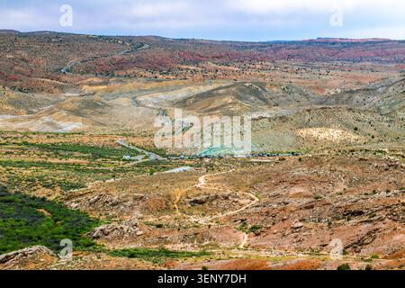 Hohe Blickwinkelaufnahme einer sich windenden Asphaltstraße, die sich durch die weite rote Felswüstenlandschaft des Canyons von Moab, Utah, schneidet. Stockfoto