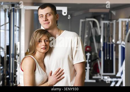 Das junge Paar steht und umschließt sich im Fitnessstudio Stockfoto