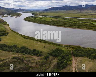 Eine malerische Szene mit einem sich windenden Fluss, der durch die grüne Landschaft von Wladiwostok, Russland, fließt. Üppiges Grün und sanfte Hügel ergänzen das Stockfoto