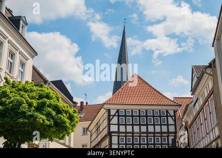 Deutschland Stadt Fachwerkhaus Turm, traditionelles europäisches Fachwerkhaus mit rotem Ziegeldach, historischer Kirchturm vor blauem Himmel mit Wolke Stockfoto