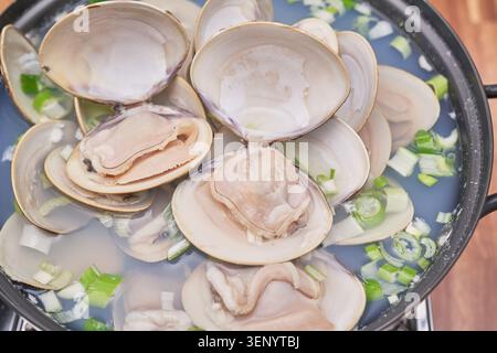 Traditionelle koreanische Gerichte umfassen frische große Biventilen, die in einer klaren Brühe gekocht werden, kombiniert mit gedämpftem weißem Reis und verschiedenen Beilagen wie scharfen Kimchi Stockfoto
