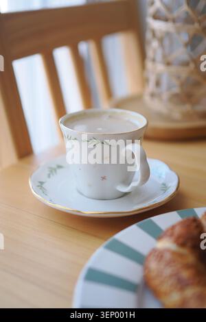 Warmes Getränk und Croissant auf einem Holztisch Stockfoto