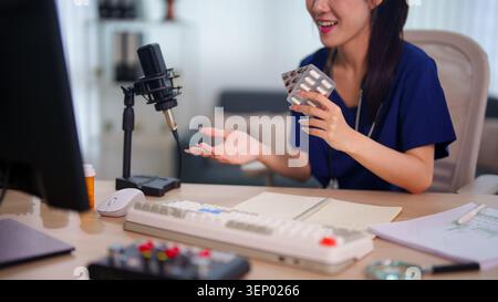 Asiatische weibliche Inhaltserstellerin, die während der Podcast-Aufnahme mit Mikrofon-Setup über Themen der Medizin und des Gesundheitswesens spricht Stockfoto