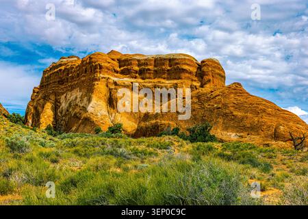 Blick aus einem hohen Winkel auf ein großes monolithisches Sandsteingestein, das sich über Wüstenebenen im Devils Garden erhebt. Stockfoto