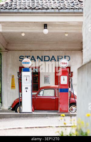 Historische Standard Bensin Tankstelle mit alten Benzinpumpen und einem roten Typ 1 klassischen Volkswagen Käfer im Norsk Folkemuseum in Oslo, Norwegen Stockfoto