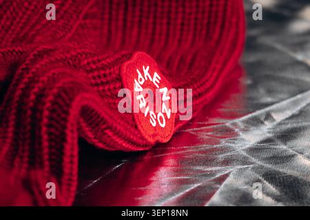 Nizza, Frankreich - 1. März 2026: Nahaufnahme eines roten Kenzo-Strickstücks mit dem ikonischen floralen Logo-Patch, der das luxuriöse Modedesign unterstreicht. Stockfoto