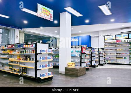 palu, Indonesien - 13. April 2026 : modernes, breites Interieur einer Apotheke in Indonesien mit einzigartiger blauer Decke und LED-Panelbeleuchtung. Es zeigt organisierte Warenregale für Gesundheits-, Lebensmittel- und Getränkeartikel sowie einen prominenten Kassenschalter. Stockfoto